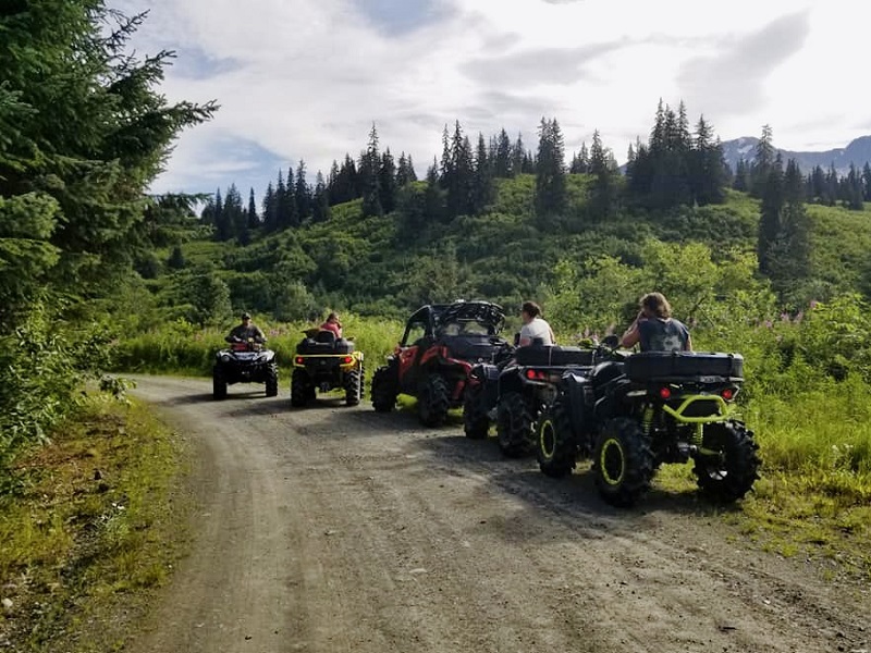 People riding off-road vehicles down a dirt road.