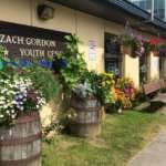 Angled view of Zach Gordon Youth Center with sign visible and flowers blooming