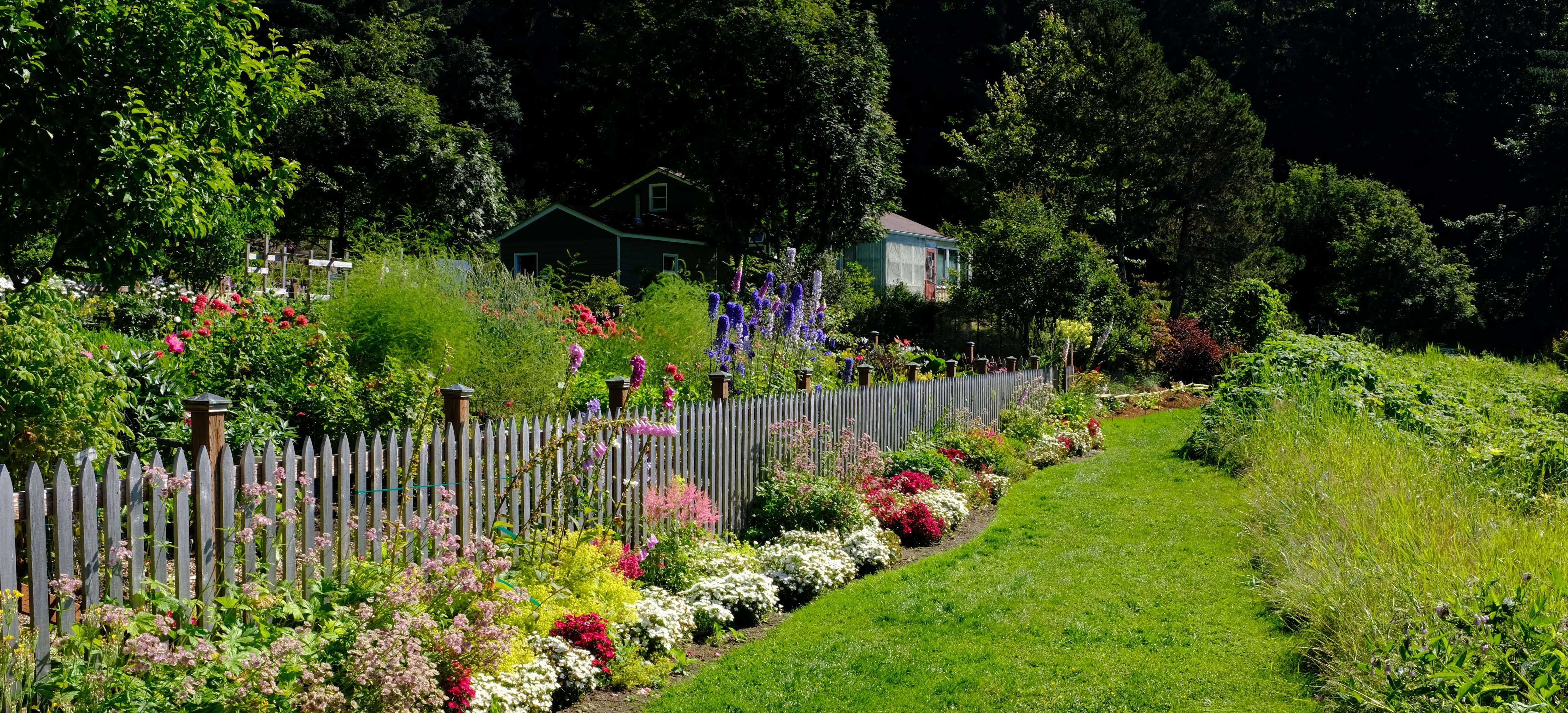 Fence with manicured flower beds and lawn pathway at the arboretum.