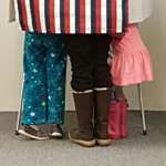 This is a picture of a voting booth with what's clearly the legs of three children showing underneath.