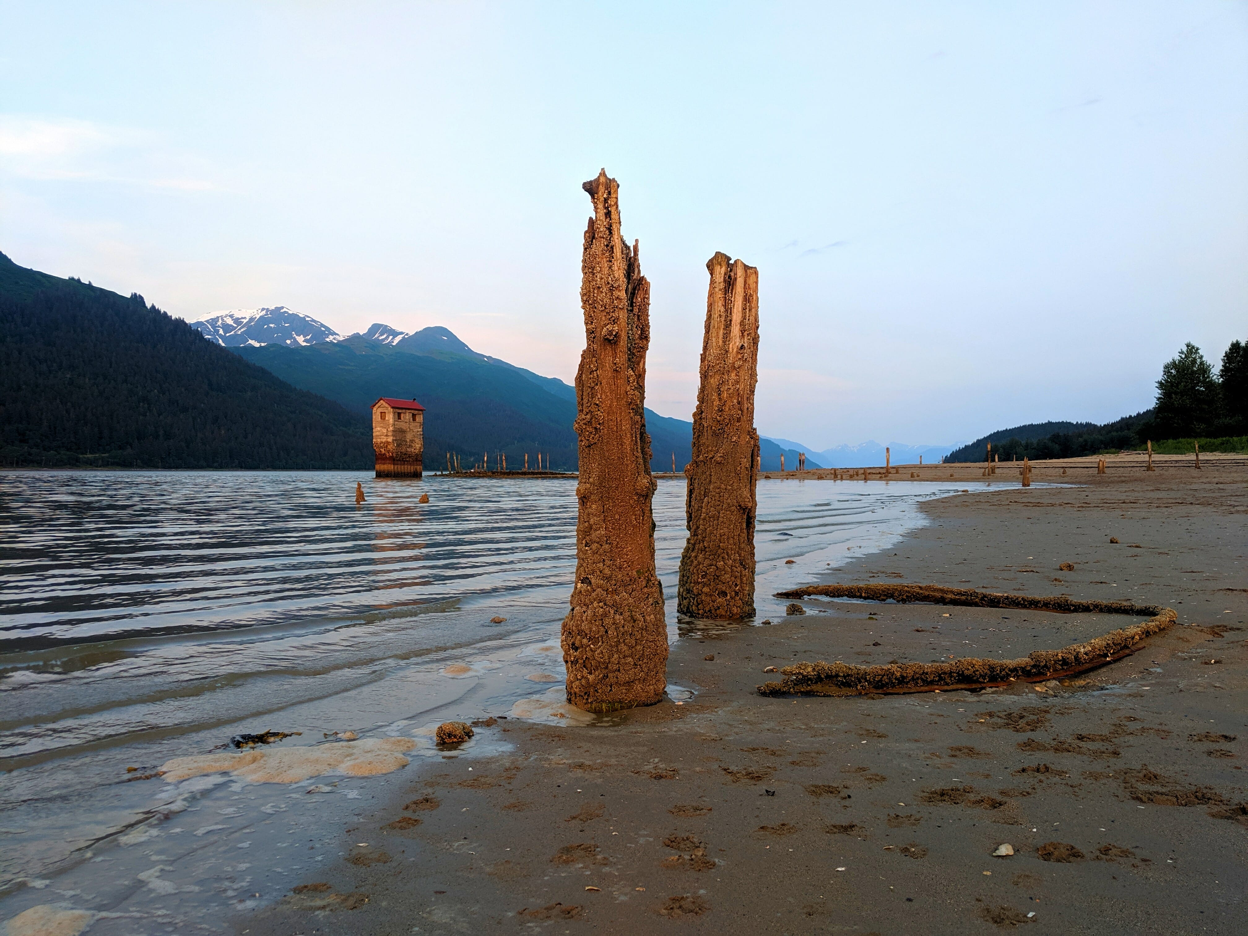 Old pilings with the pump house in the distance at Sandy Beach