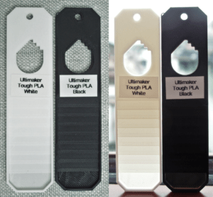 Swatches of Ultimaker Tough PLA in black and white. The two swatches are shown frontlit and backlit. The black TPLA is visibly translucent in the 0.2mm thick layer only; the white TPLA allows some light through at all thicknesses.