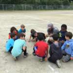 This images shows a youth sports team and coach circled up in dicussion.