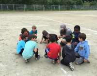This images shows a youth sports team and coach circled up in dicussion.