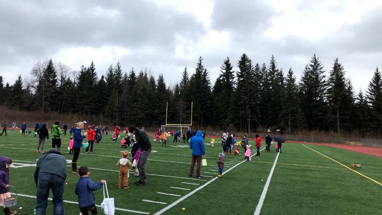 Lots of kids and parents collecting eggs at the Easter Egg Hunt on Adair Kennedy field.