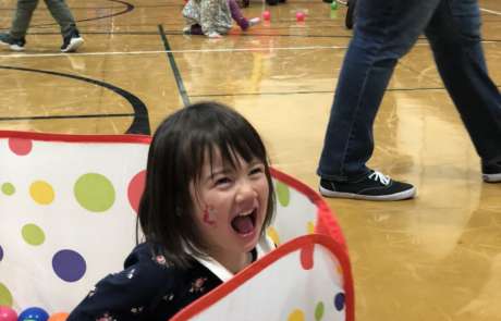IMG_1927 A young girls laughs while playing in a ball pit at Preschool Open Gym.