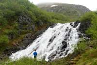 This is a picture of a beautiful Juneau waterfall and a person looking at it.
