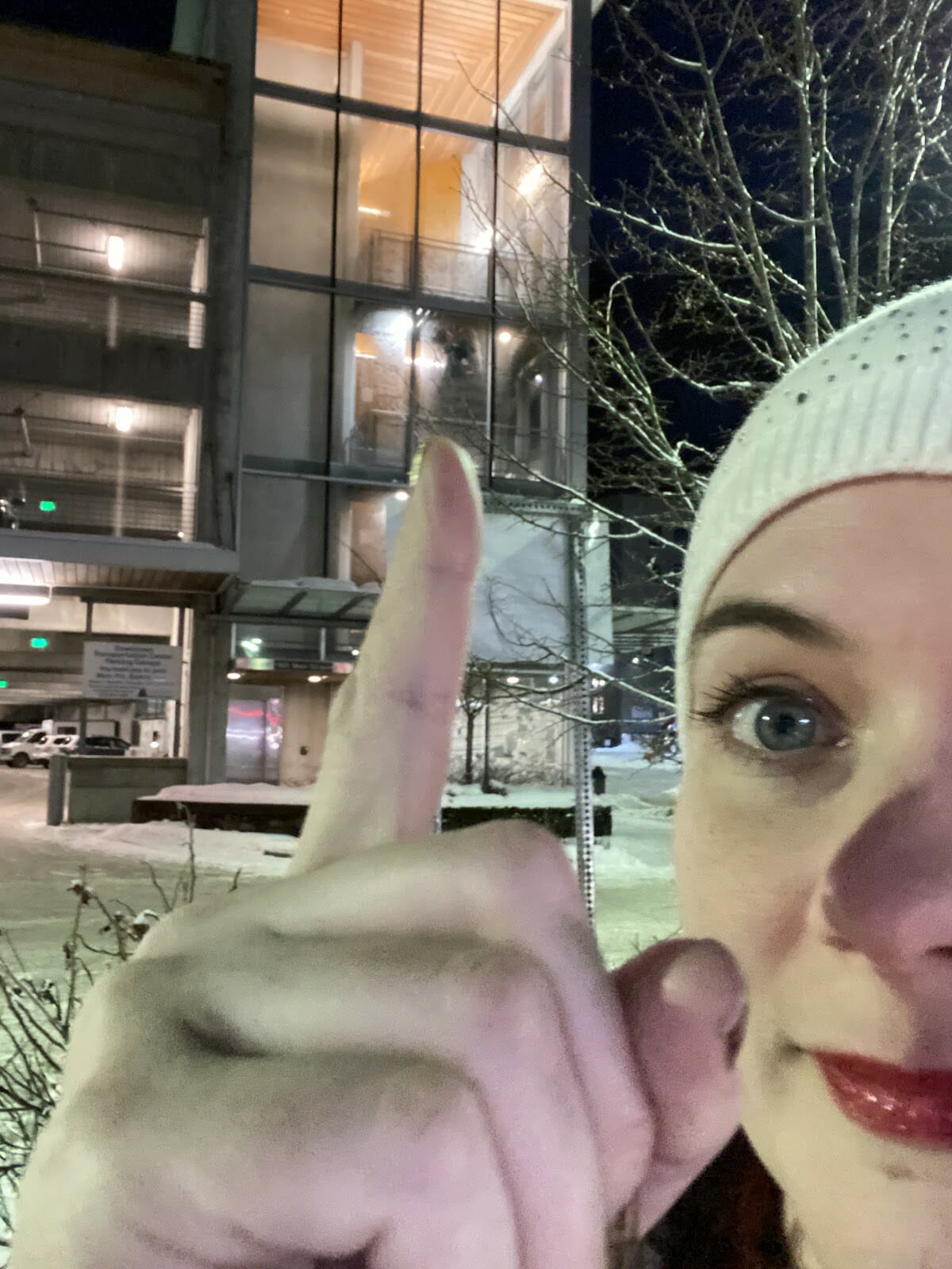 Candy Cane Hunt selfie of woman pounting up at the candy cane in the window at the parking garage.