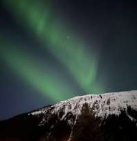 Photo of green aurora above snowy mountain