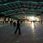 Photo of people skating at Treadwell Arena ice rink lit with rainbow lights