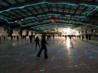 Photo of people skating at Treadwell Arena ice rink lit with rainbow lights