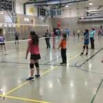 Photo of two teams of children standing on either side of a volleyball net