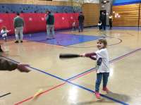 Photo of small child swinging wiffle bat in gymnasium