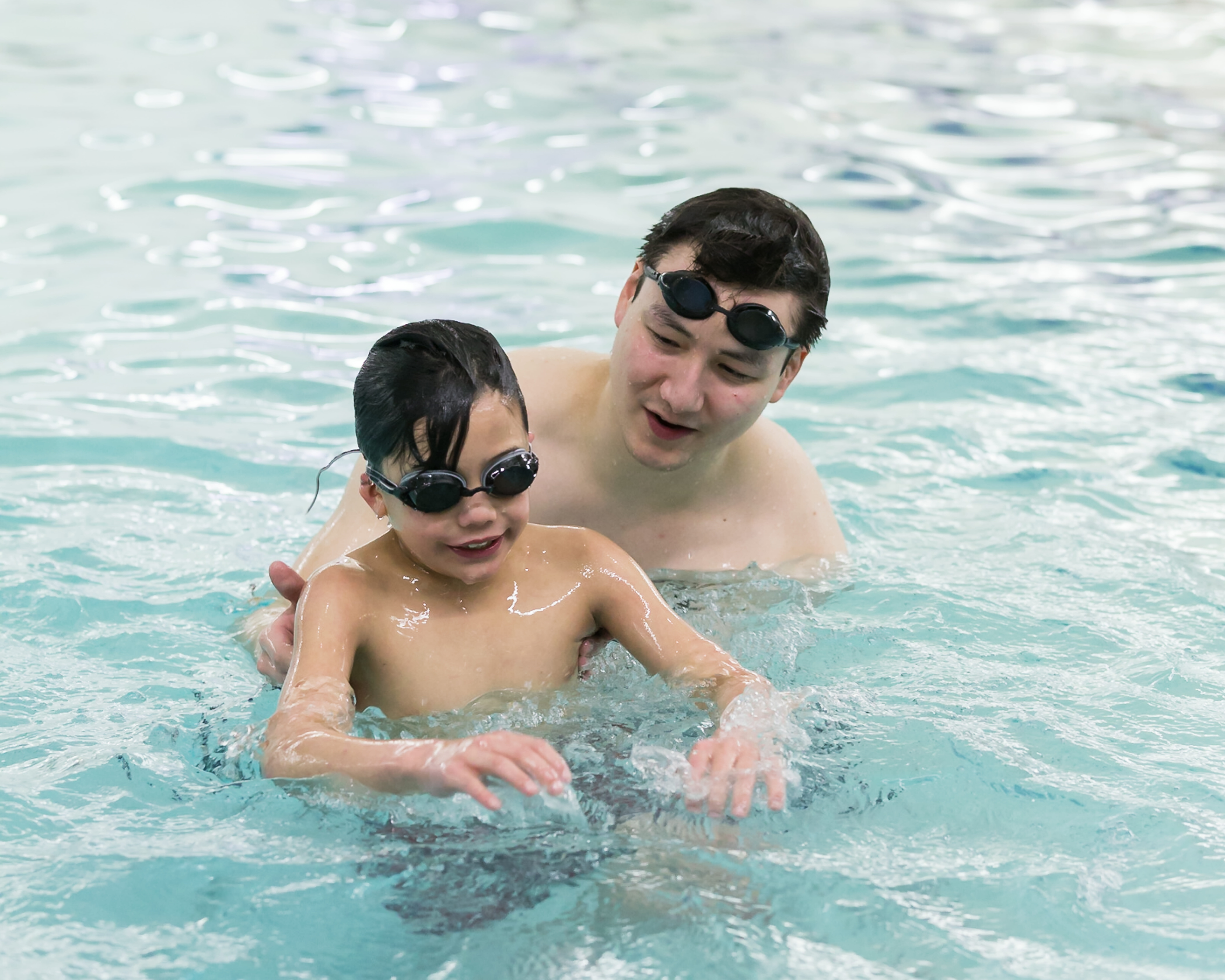 Photo of adult swimmer supporting child in pool