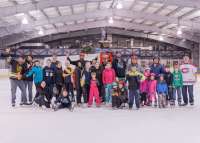Photo of children and adult skaters posing in front of Zamboni on Treadwell Arena ice rink