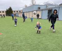 Photo of small children and adult instructor playing with soccerball outdoors