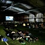 Photo of people stretched out on the Field House turf watching a movie