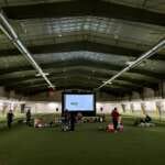 Photo of kids and adults watching a movie on the Field House turf.