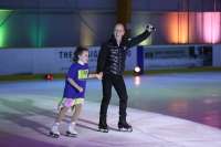Scott Hamilton holding hands with a young figure skater on the ice