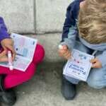 Photo of two young children filling out Passport to Play booklets