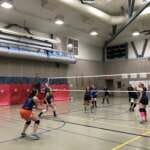 Photo of two women's volleyball teams mid-match