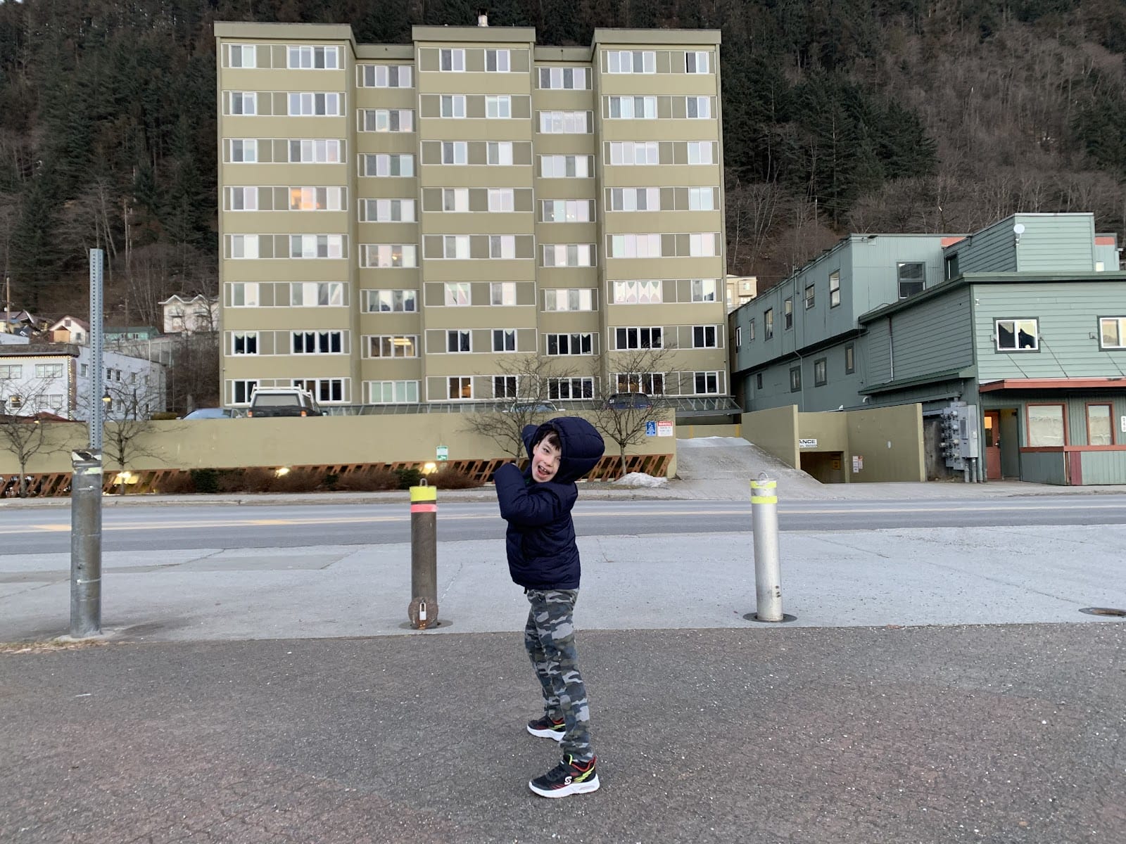 Child pointing at a tall building behind him.