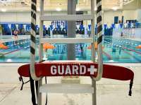 Back view of lifeguard chair, with red lifesaving device reading GUARD.