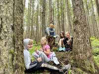 Photo of five young children smiling and sitting in the woods