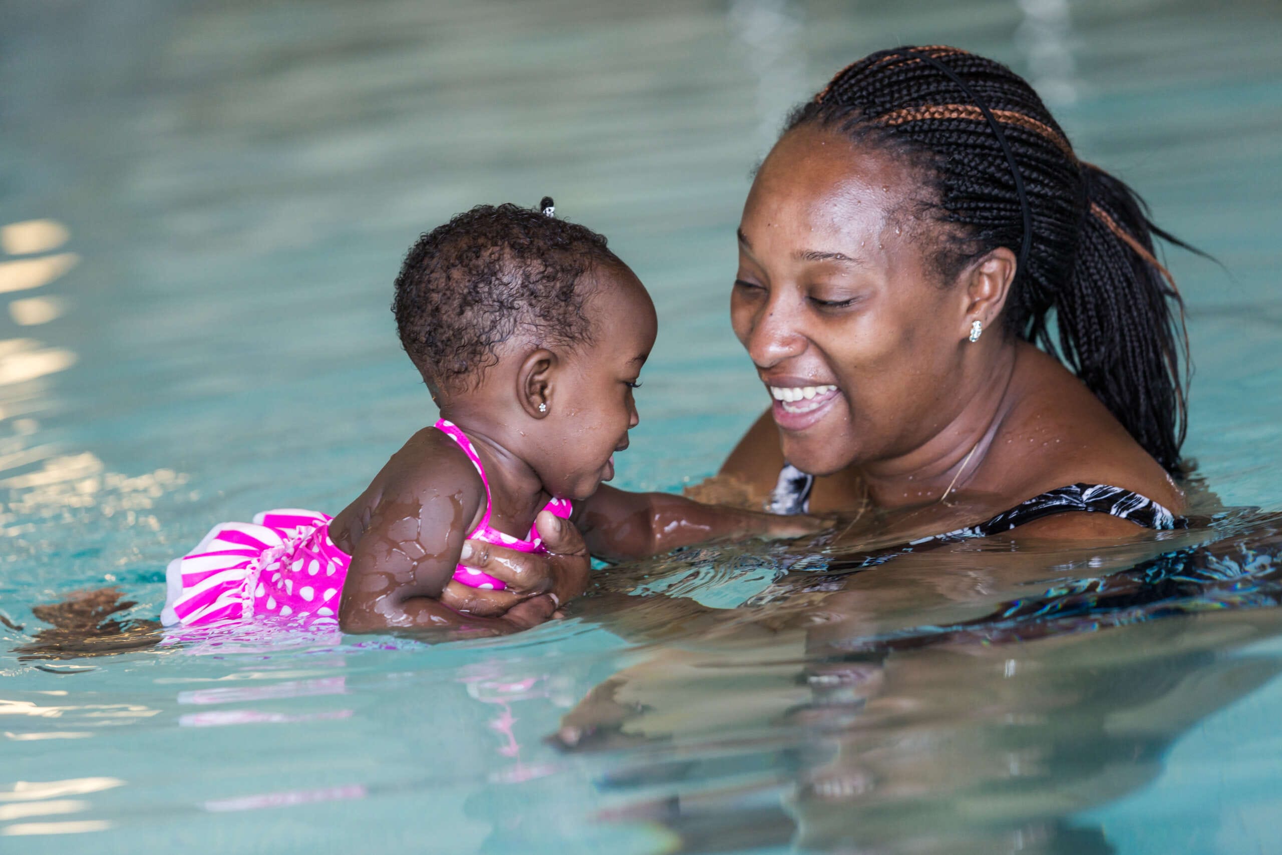 Photo of smiling adult woman and small child together in the pool