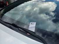 Photo of parking ticket with CBJ logo tucked under windshield wiper