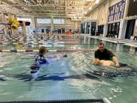 Two aspiring water safety instructors support floating swimmers in the pool.