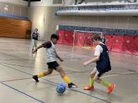 Two players fight for control of the ball on an indoor soccer court