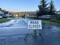 Road closed sign with floodwaters visible over the road in the distance
