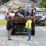 Two men standing behind a truck.