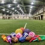 A pile of footballs, kickballs and soccer balls gathered on the Field House turf