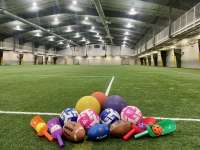 A pile of footballs, kickballs and soccer balls gathered on the Field House turf