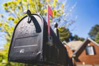 Photo of mailbox with flag upraised silhouetted against the blue sky