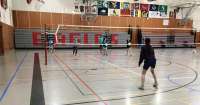 A young volleyball player prepares to receive serve from across the net.