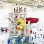 Swimmers line up at the top of the yellow water slide at Dimond Park Aquatic Center