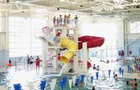 Swimmers line up at the top of the yellow water slide at Dimond Park Aquatic Center