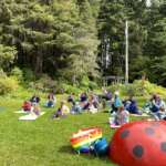 Children sprawl on the Arboretum lawn, with an inflatable lady bug in the foreground.