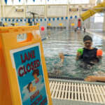 An aquatics instructor helps a young swimmer in the pool