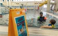 An aquatics instructor helps a young swimmer in the pool