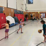 Young children practice dribbling in a gymnasium