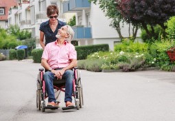 Woman pushing man in wheelchair