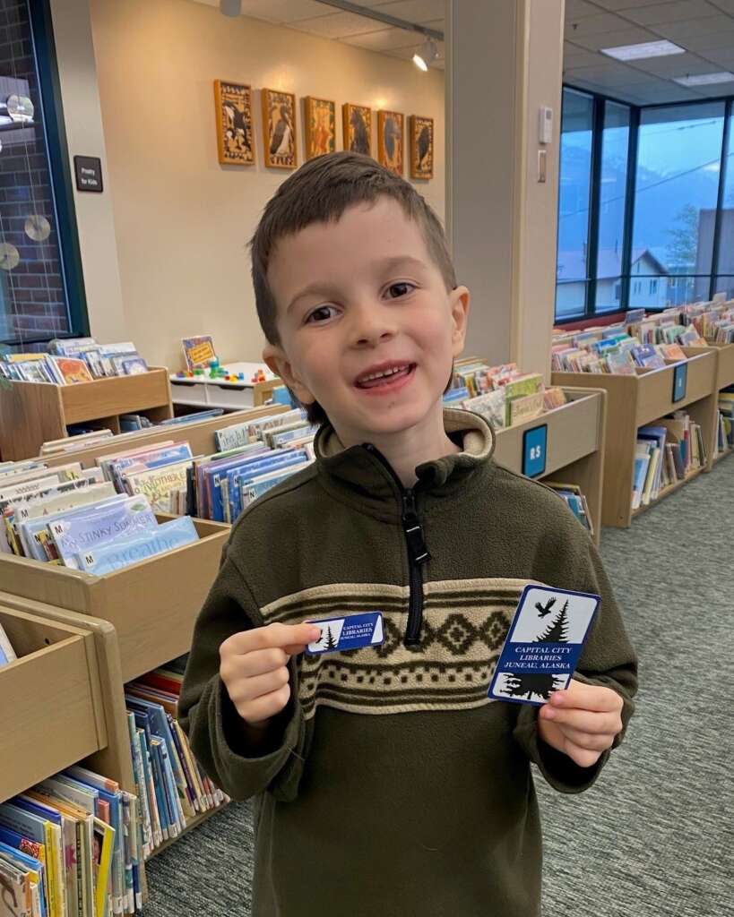 webpic2 Child holding two library cards in the library