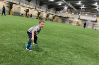 Kid squats and looks at the camera while playing at the Dimond Park Field House.
