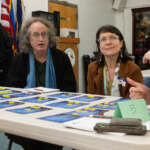 Juneau residents participate in a CBJ Community Compass workshops. Residents talk to each around a table with cards and tokens.