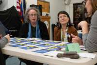 Juneau residents participate in a CBJ Community Compass workshops. Residents talk to each around a table with cards and tokens.