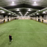 One person walks across an empty field inside the Dimond Park Field House.